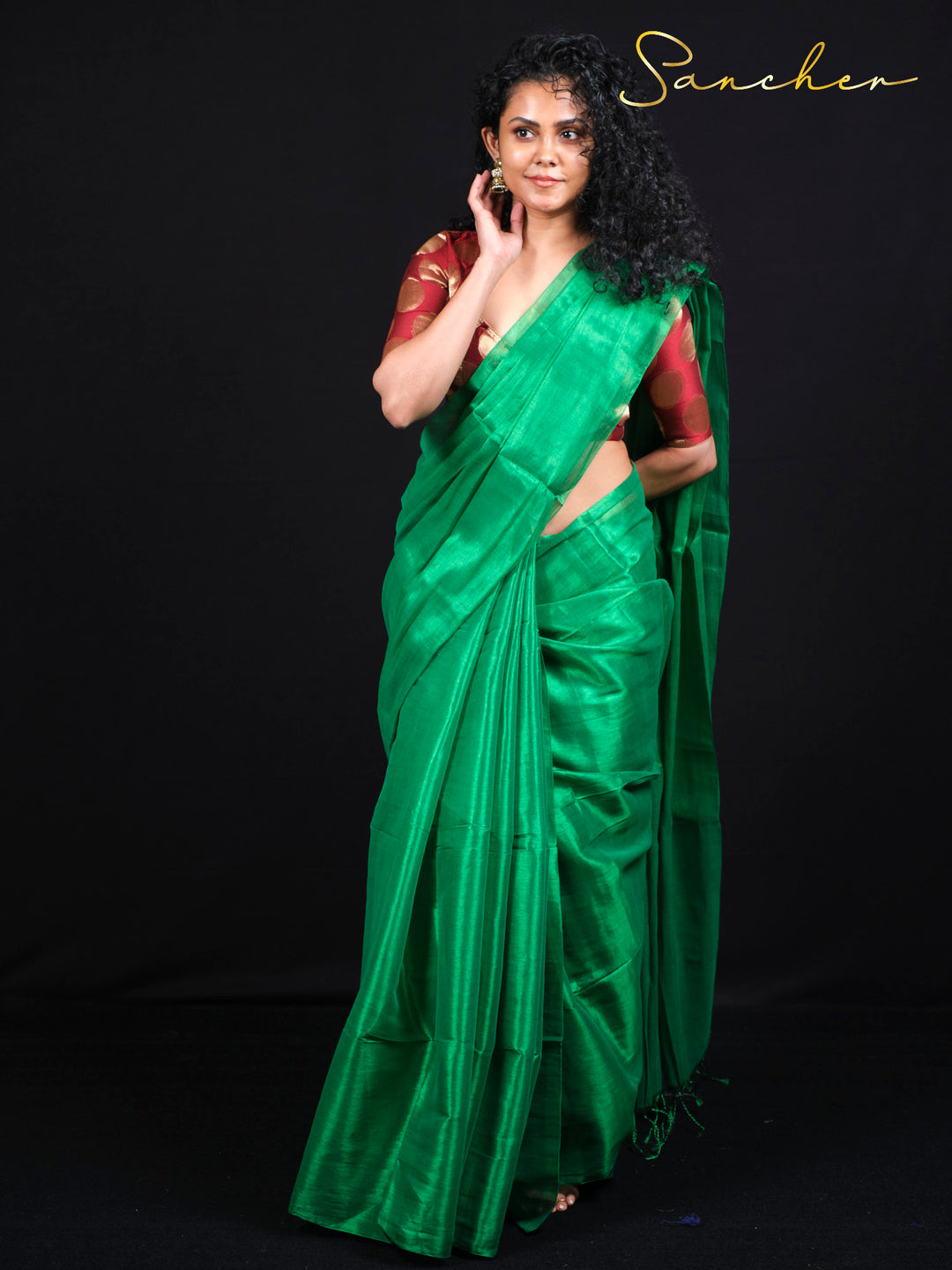 Woman wearing emerald green mul zari saree with burgundy polka dot blouse - front view full length