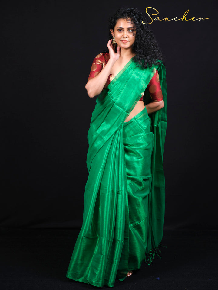 Woman wearing emerald green mul zari saree with burgundy polka dot blouse - front view full length