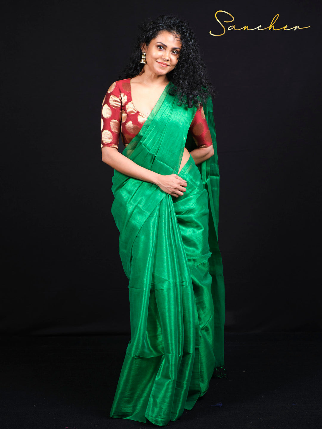 Standing pose of emerald green mul zari saree with golden polka dot blouse piece styling