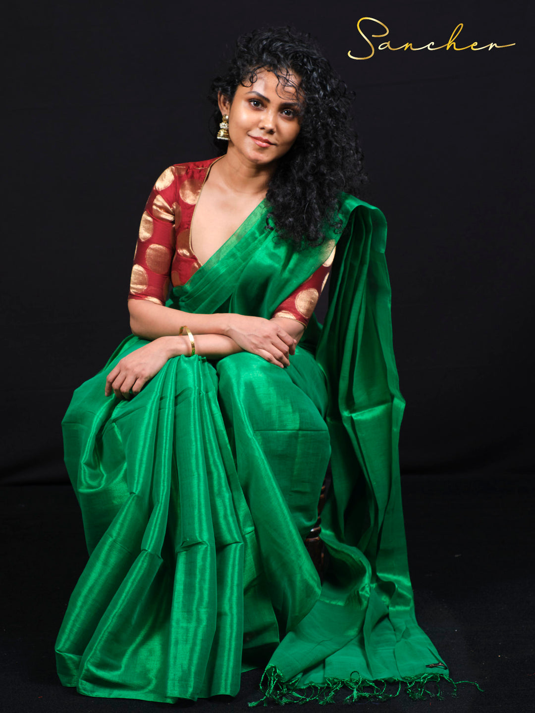 Model in green mul zari silk saree sitting pose showing drape and fabric flow details