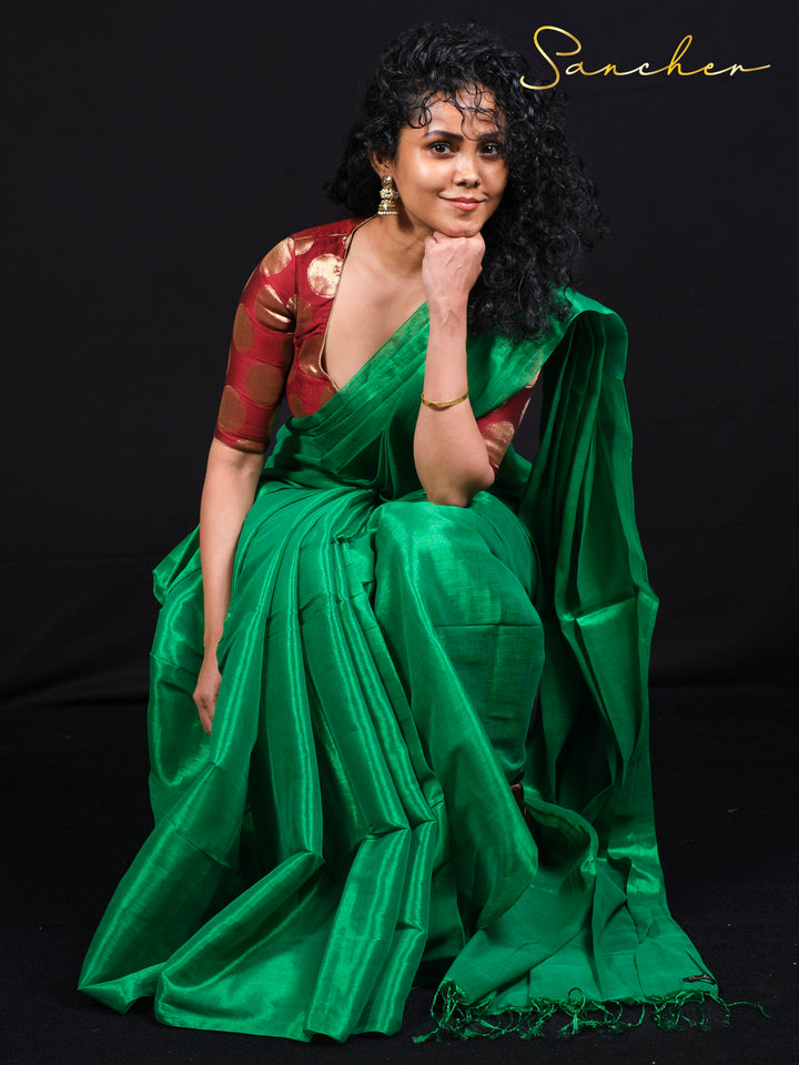 The model is wearing a green Mul Zari silk saree and is sitting to show how the fabric drapes and flows.