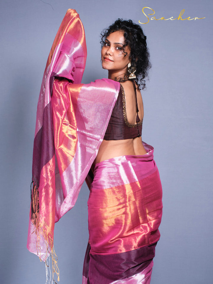 Woman wearing pink purple Mul Zari saree with golden threads and traditional Indian jewelry against gray background