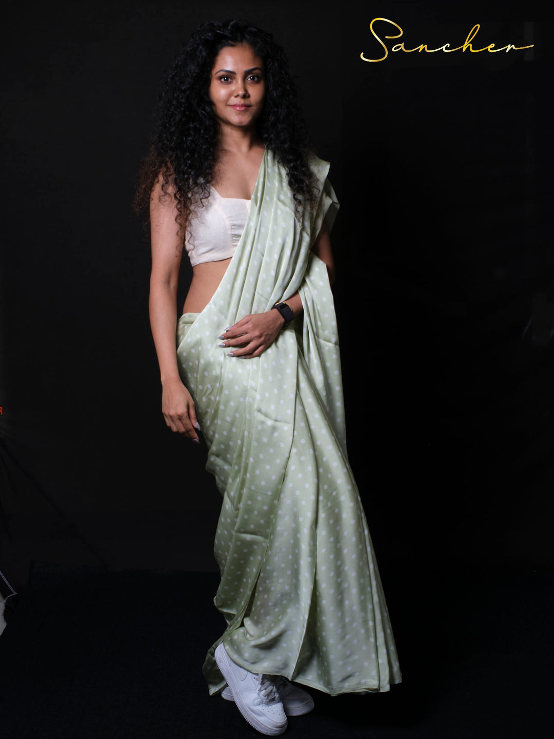 Woman wearing sage green modal silk saree with white polka dots and white crop top