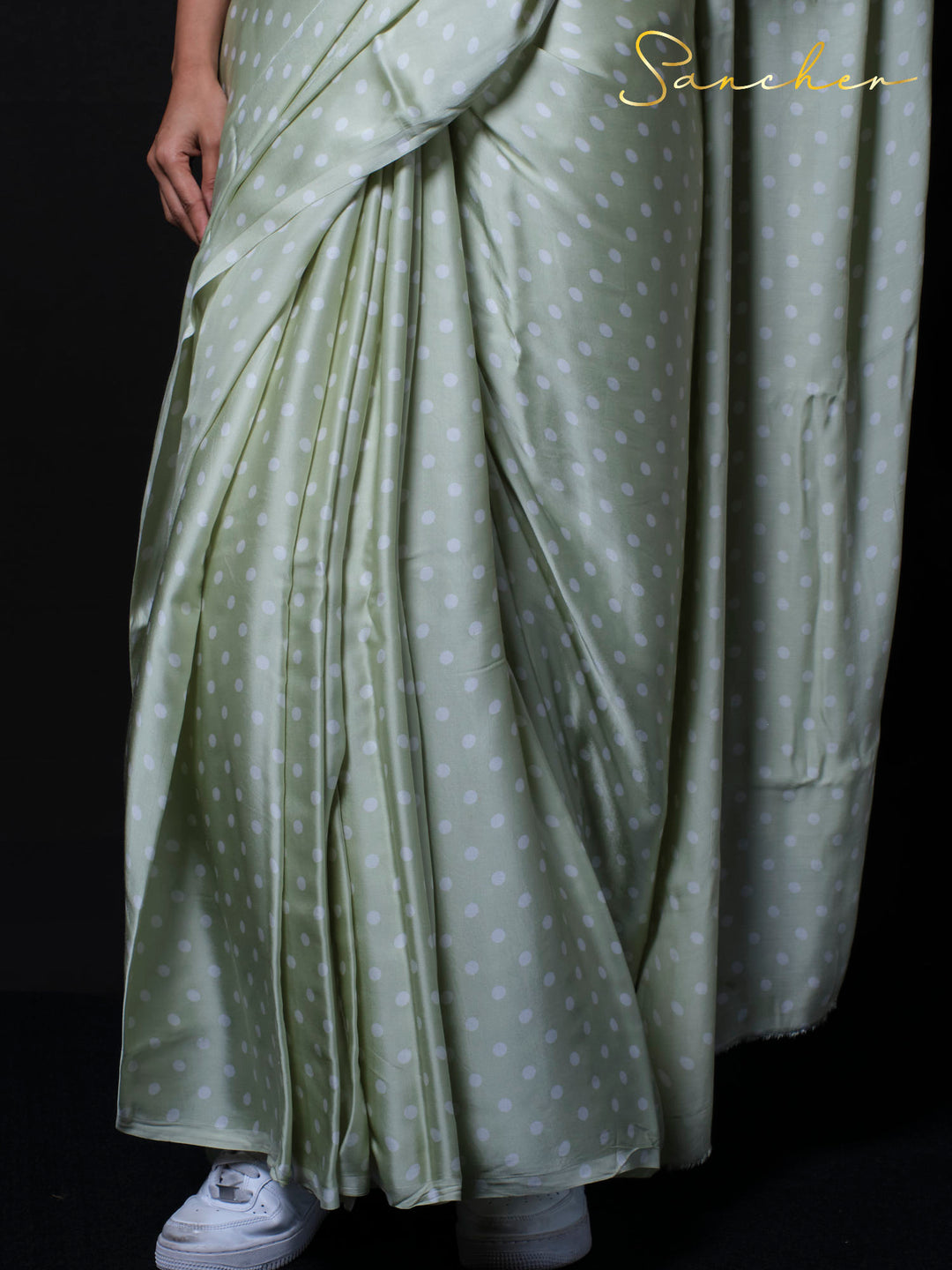 Detail shot of sage green modal silk fabric with white polka dot pattern