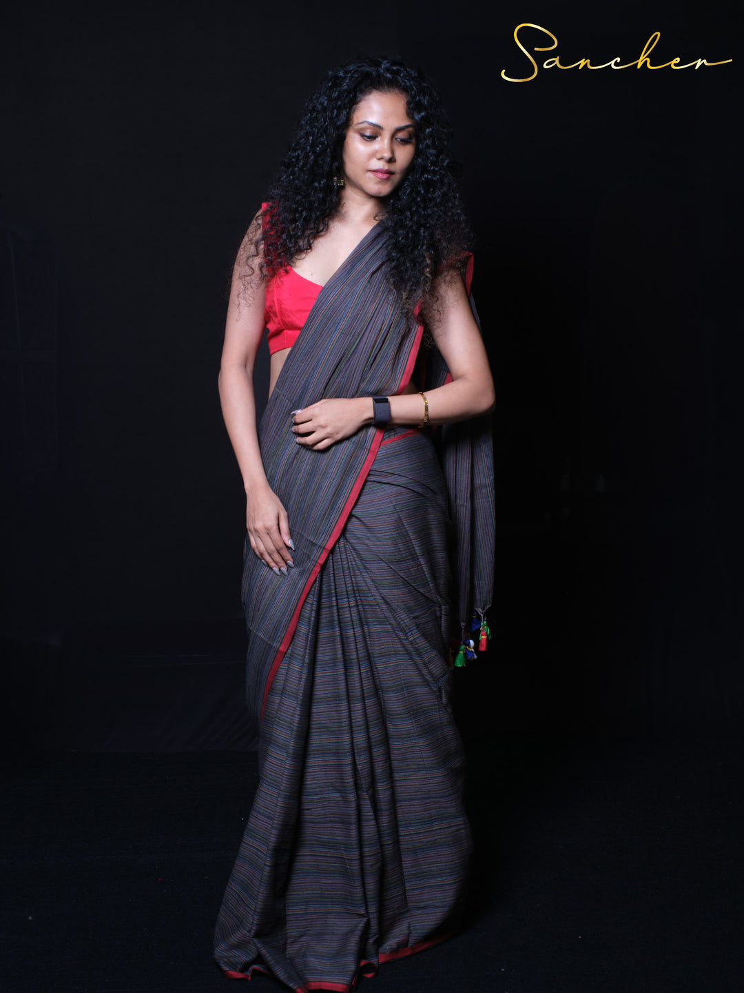 Handcrafted mulmul cotton Coastal Charm saree in dark green with red contrast border and rainbow accents
Ethnic mulmul cotton handloom saree with airy fabric texture featuring charcoal base and colorful pallu tassels.