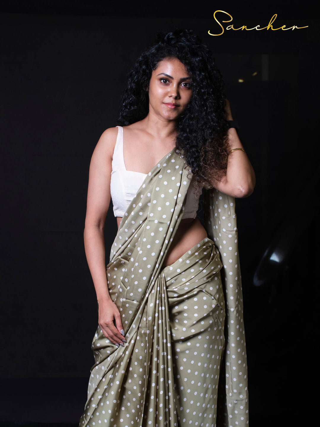 Close up of woman in sage green polka dot saree demonstrating graceful hand poses and styling