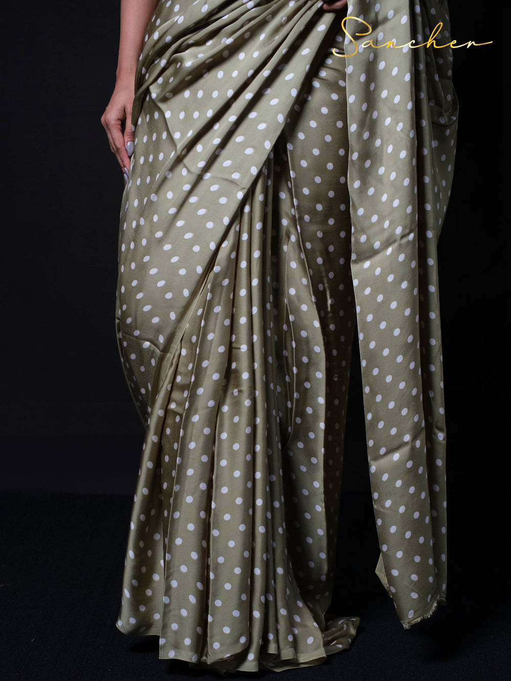 Detail shot of polka dot modal silk saree fabric showing white dots pattern on sage green base