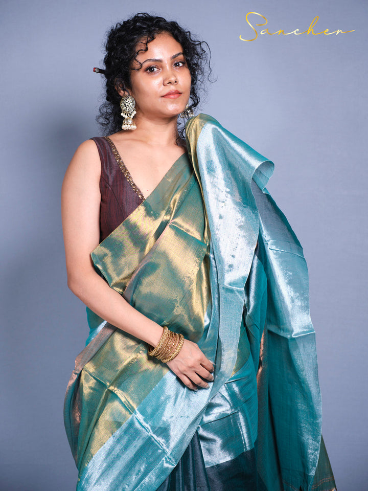 Close-up of mul zari saree fabric showing color-changing shimmer effect in teal and gold