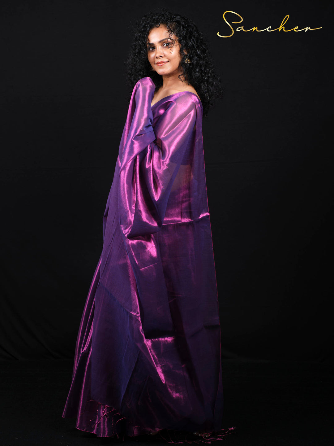 Woman wearing purple magenta mul zari saree in elegant pose against black background