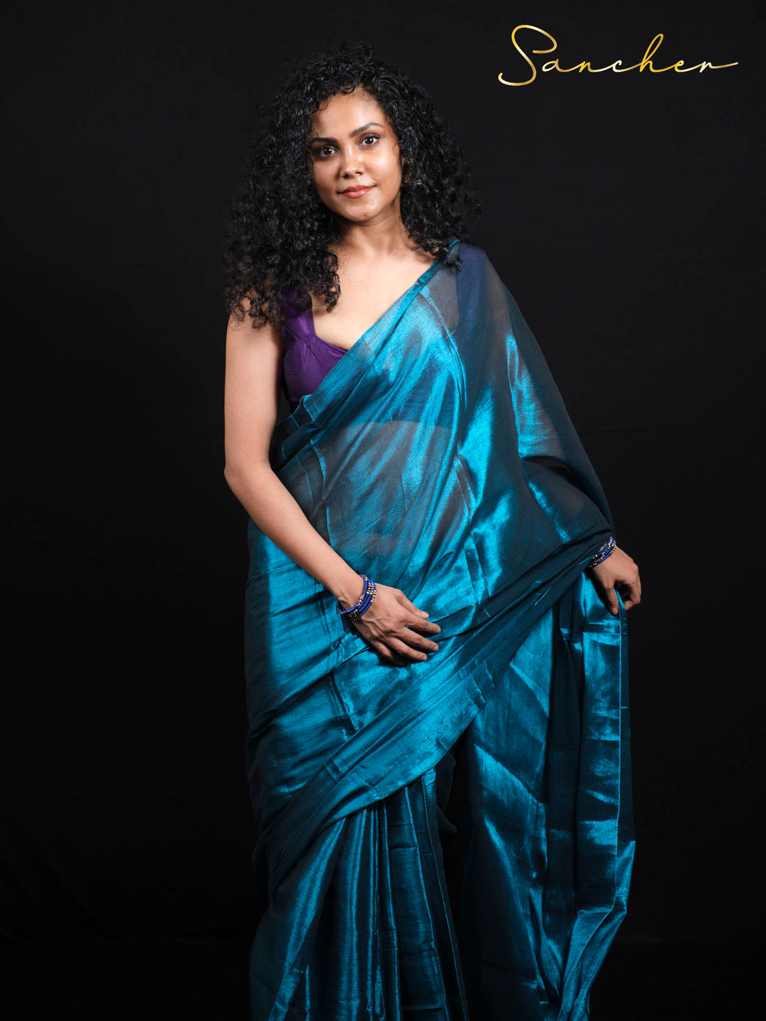 Beautiful woman wearing teal blue Mul Zari saree with purple blouse, showing elegant draping style for office wear