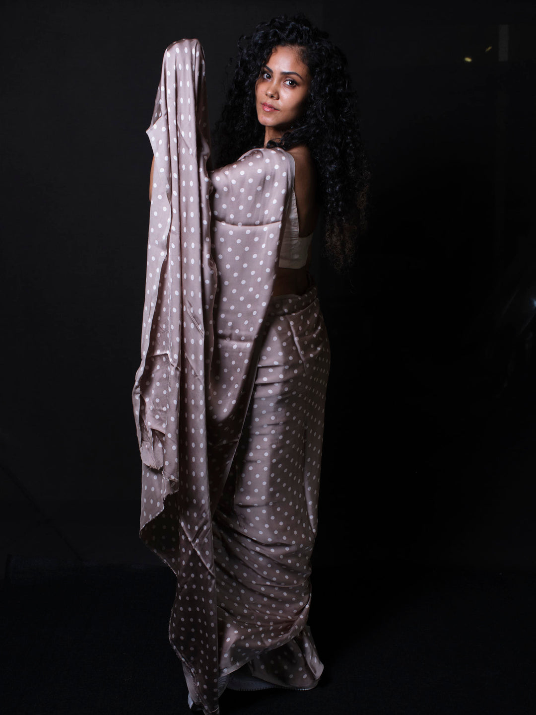 Woman adjusting polka dot modal silk saree pallu showcasing soft silk fabric texture