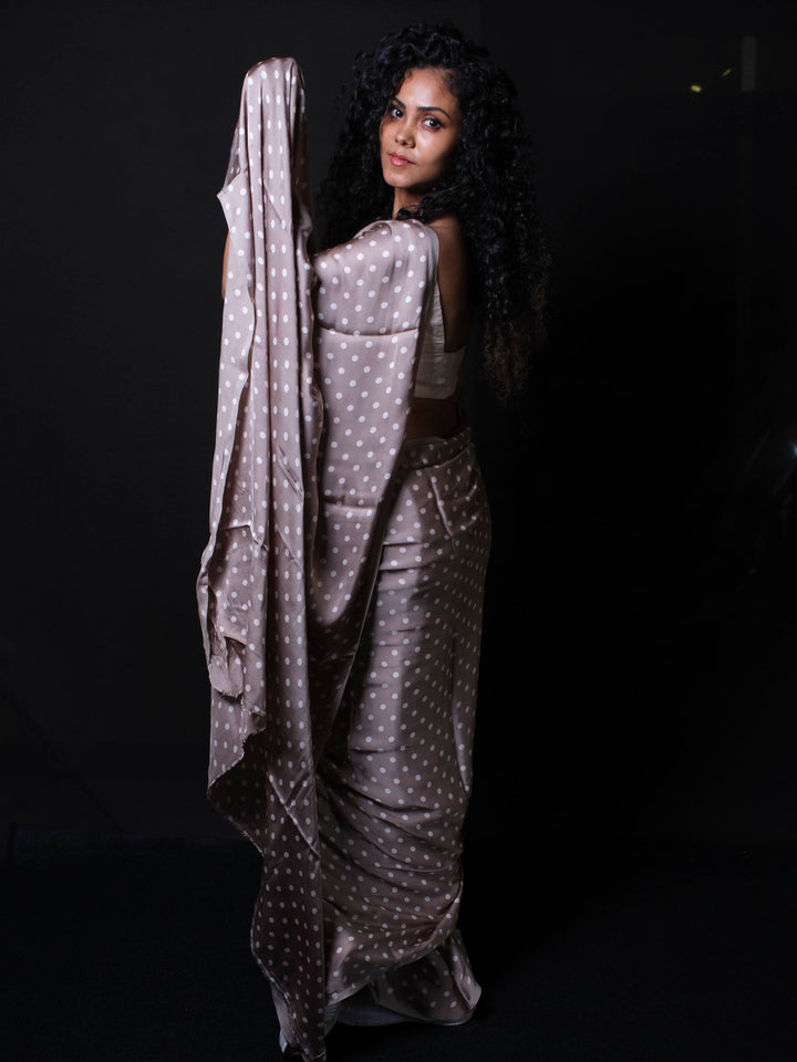 Woman adjusting polka dot modal silk saree pallu showcasing soft silk fabric texture