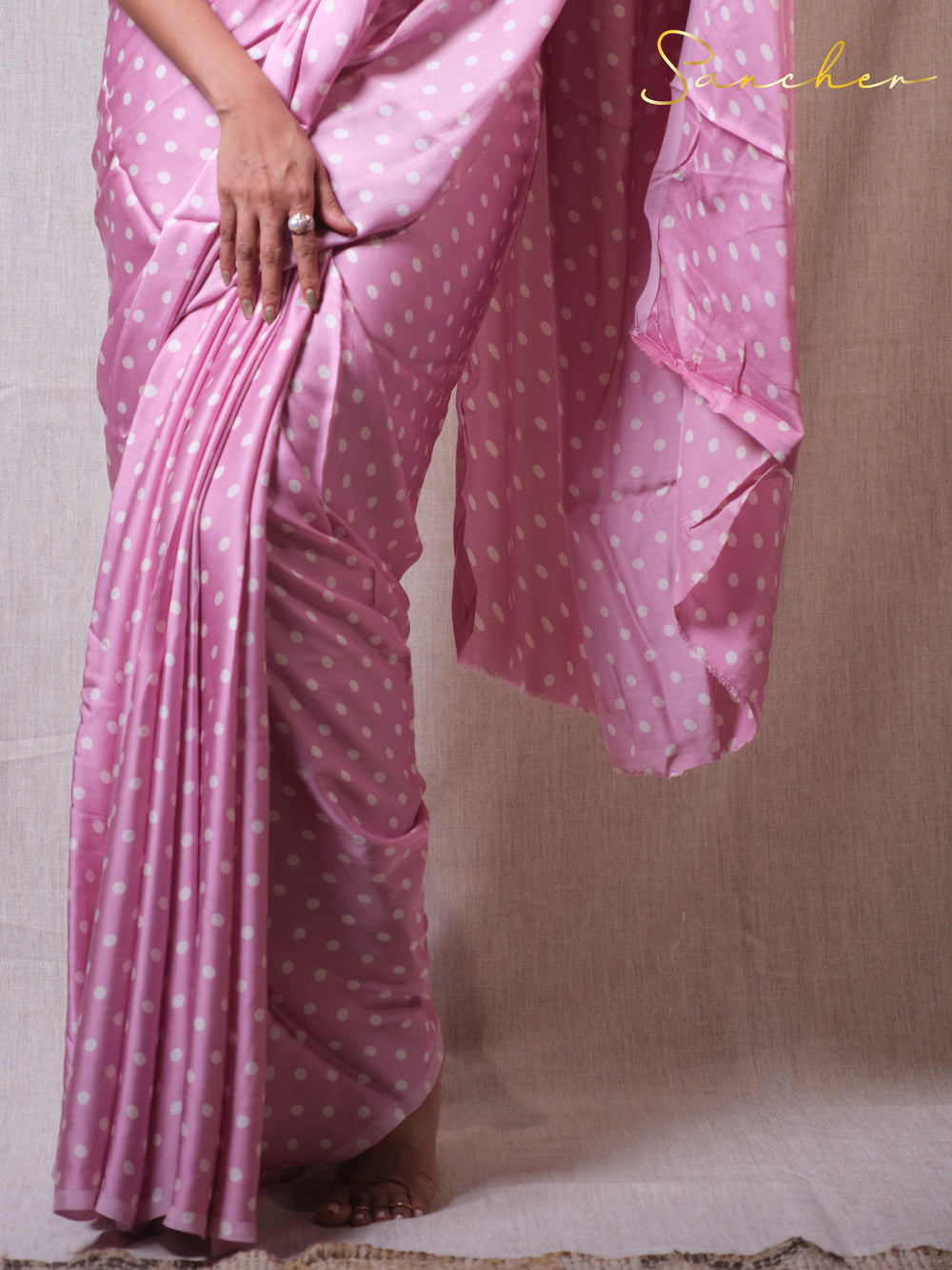 Pink saree with white polka dots on a plain background