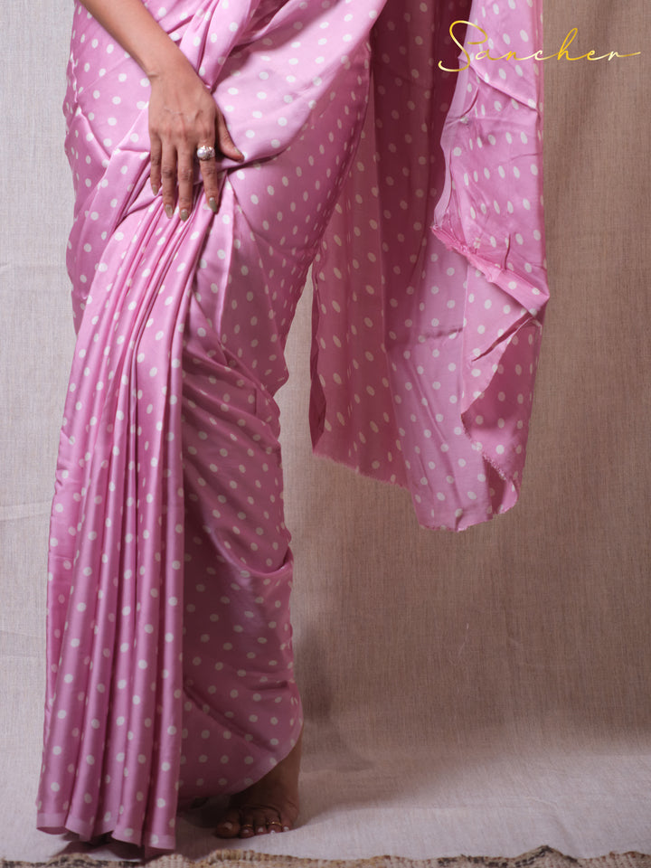 Pink saree with white polka dots on a plain background