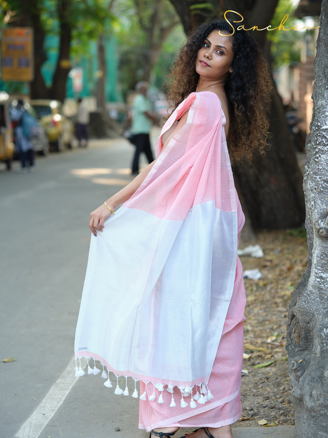 Full-length view of a woman in a pink and white mulmul cotton saree, showcasing its elegant drape and comfort, perfect for casual sarees for office wear available at best saree shops in Anna Nagar.