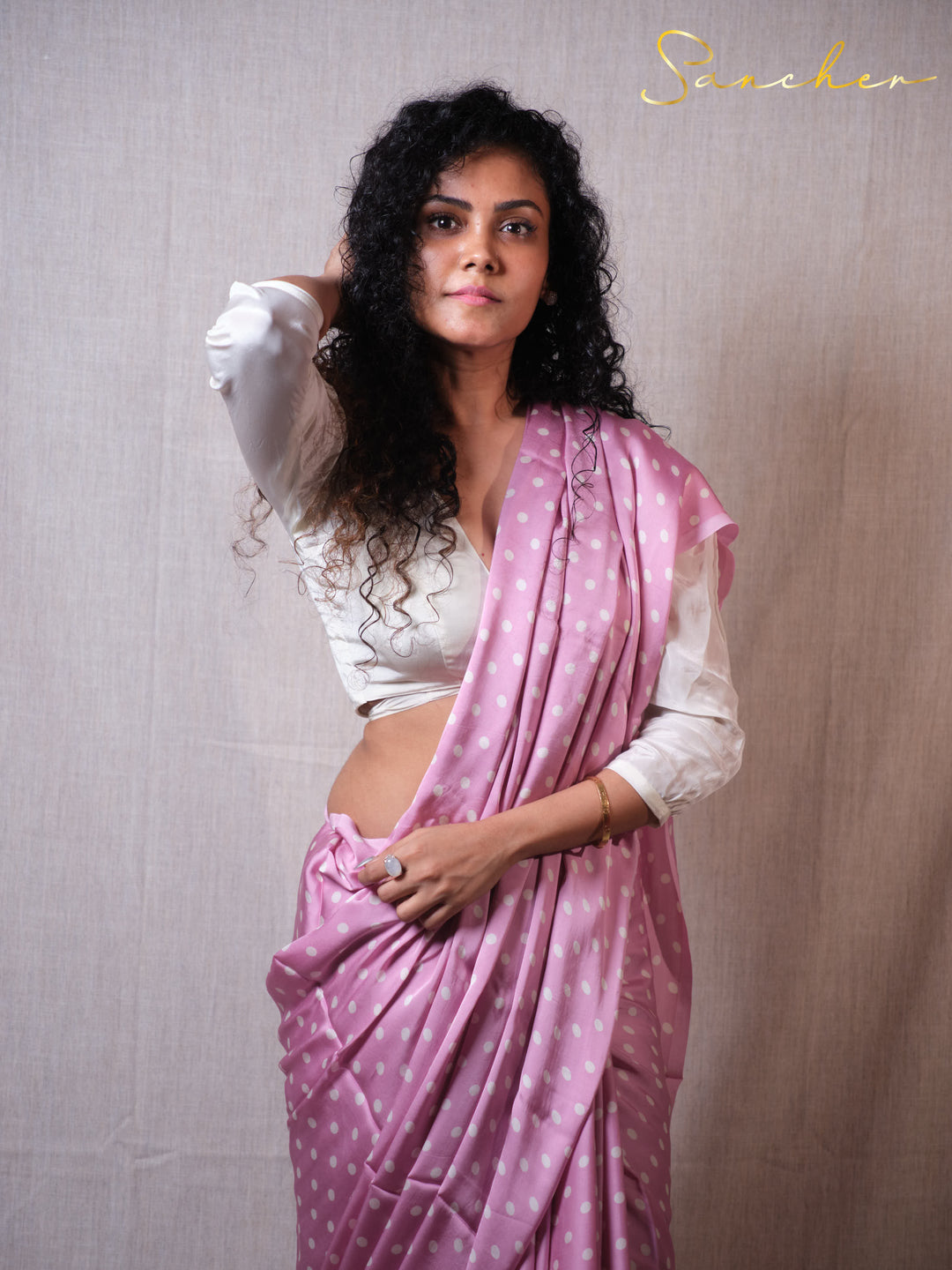 Woman in pink polka dot modal silk saree with white blouse posing elegantly