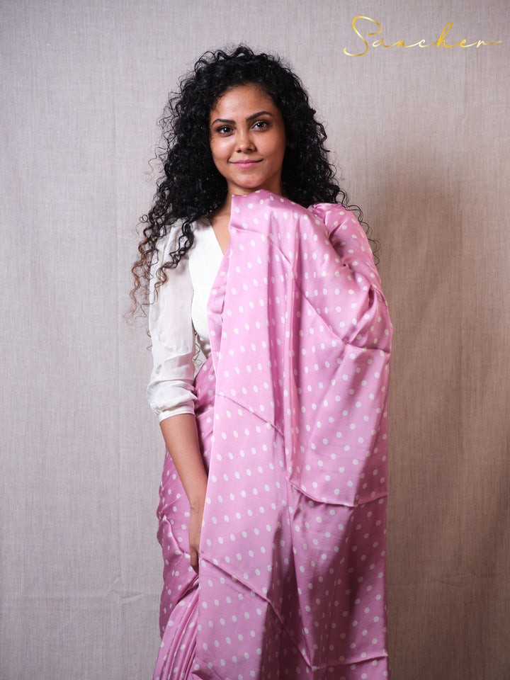 Sancher wearing a pink saree with white polka dots against a plain background