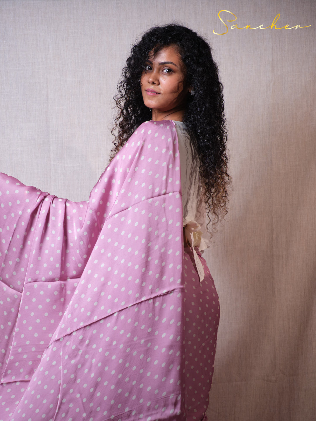 Woman wearing a pink polka dot dress with a plain background