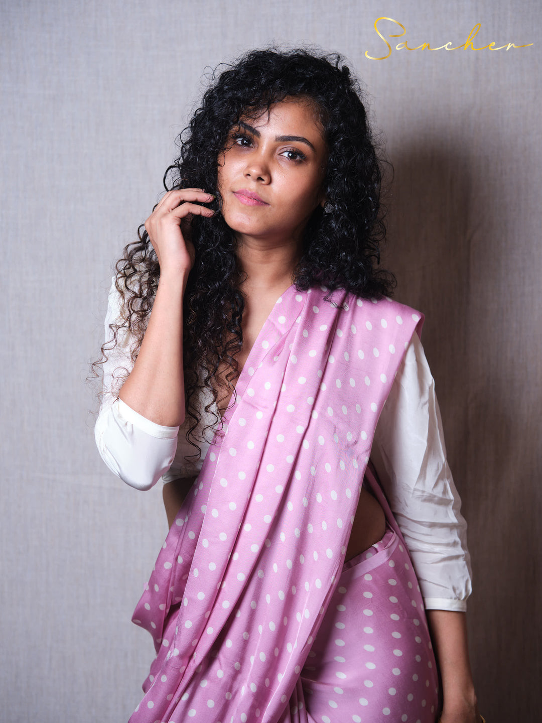 Sancher wearing a premium pink Modal Silk saree with white polka dots against a plain background