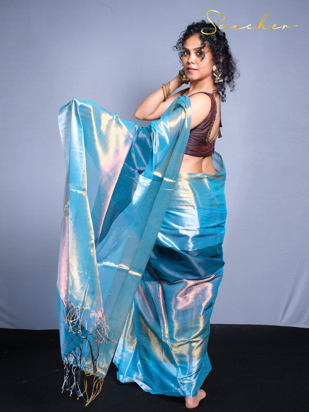 Woman wearing shimmery blue mul zari saree with burgundy blouse in studio photoshoot