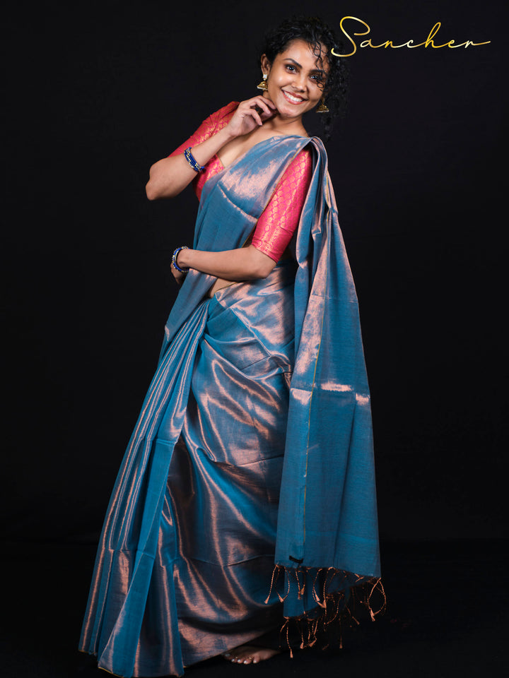 Smiling woman wearing Sancher Serence Sea Blue Mul Zari saree with pink brocade blouse and traditional gold jewelry