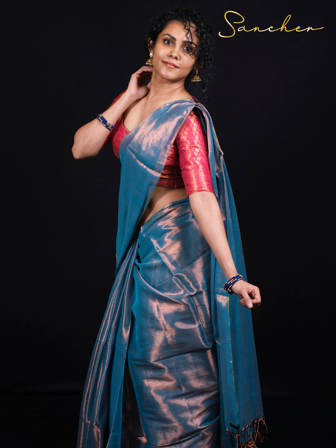 Woman wearing Sancher Serence Sea Blue Mul Zari saree with pink brocade blouse and traditional gold jewelry
