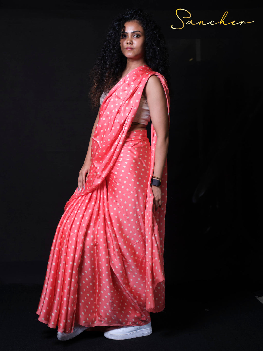 Side profile of model wearing lightweight modal silk saree in coral pink showing graceful silhouette and fabric flow