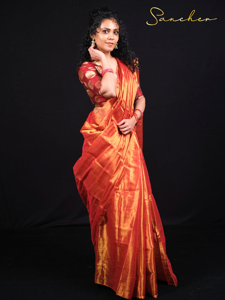 Side profile of model in sunset orange Mul Zari silk saree highlighting the elegant drape and shimmer