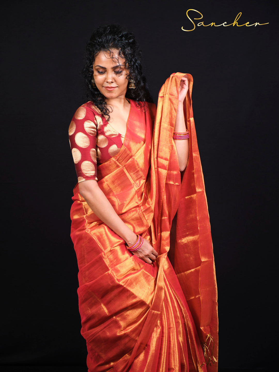 Model displaying full-length sunset orange Mul Zari silk saree with traditional styling and gold accessories