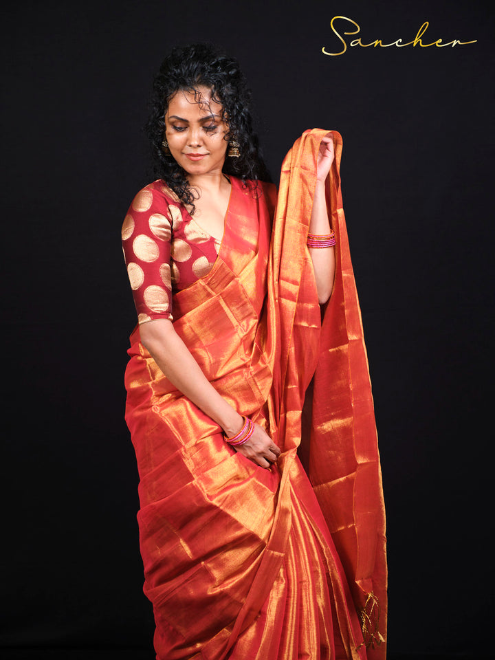 Model displaying full-length sunset orange Mul Zari silk saree with traditional styling and gold accessories