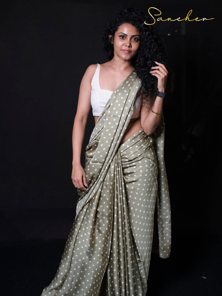 Woman wearing olive green polka dot modal silk saree with white crop top looking elegant and confident

