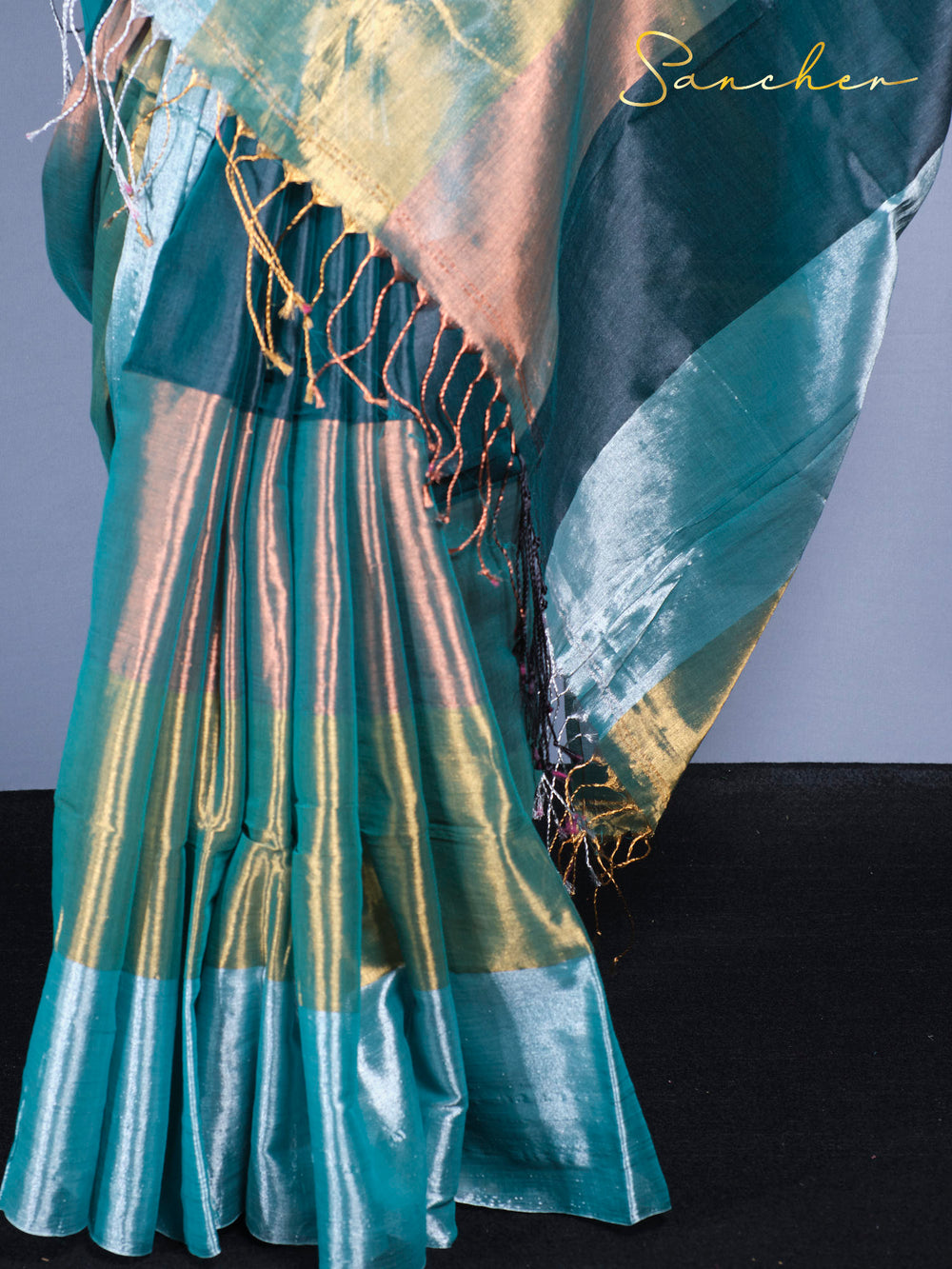 Close-up of mul zari saree fabric showing color-changing shimmer effect in teal and gold