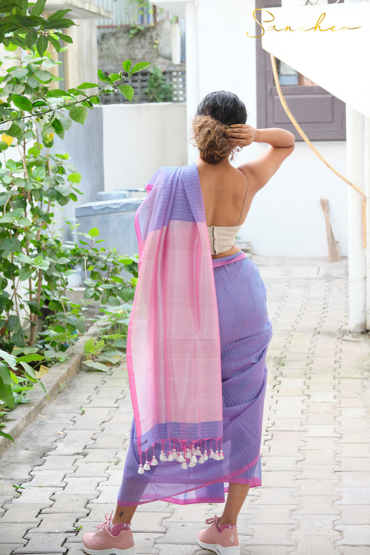 Woman adjusting hair, wearing backless blouse with lavender and pink mul cotton saree from Anna Nagar boutique, showcasing professional and casual office wear sarees available at best shops and online.