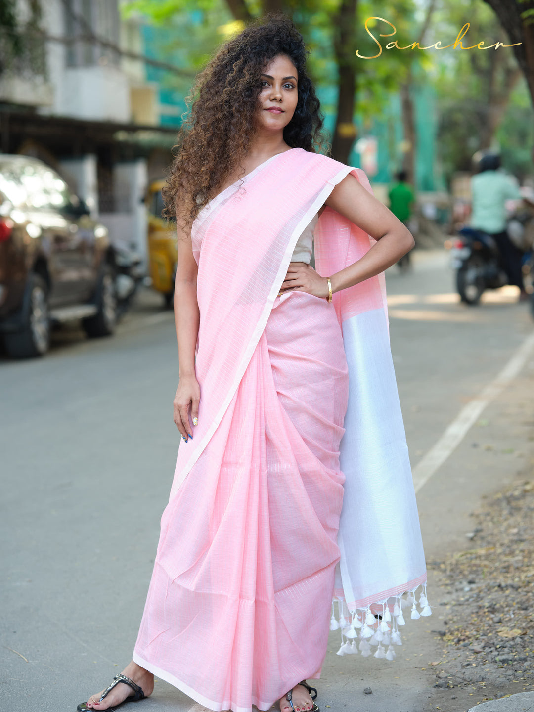 Woman wearing a pink and white mul cotton saree on a city street, demonstrating its suitability as professional office wear. Keywords: Workwear sarees, Professional Office wear Sarees, Casual Sarees for Office Wear, Pink sarees Online.