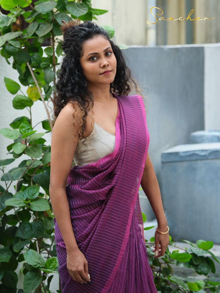 Woman in a purple striped mul cotton saree with a beige blouse, posing confidently against a backdrop of plants, ideal for office settings. Keywords: Workwear sarees, Professional Office wear Sarees, Best Sarees Shops in Anna Nagar, Casual Sarees for Office Wear.