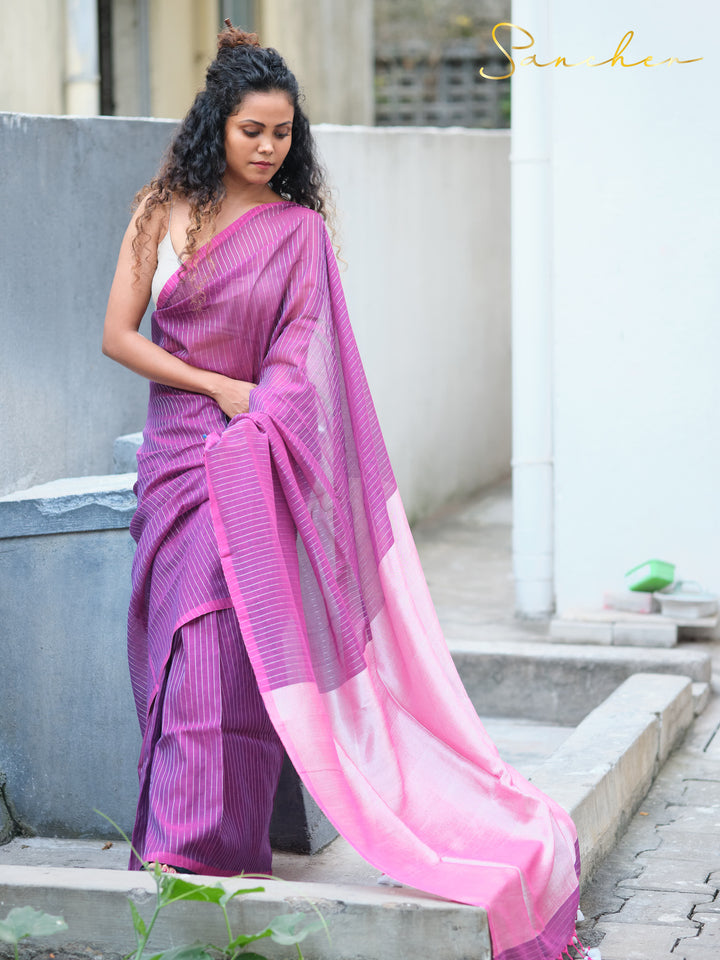 Woman seated wearing purple striped mul cotton saree with pink border, featuring professional office wear sarees available online from Sancher.