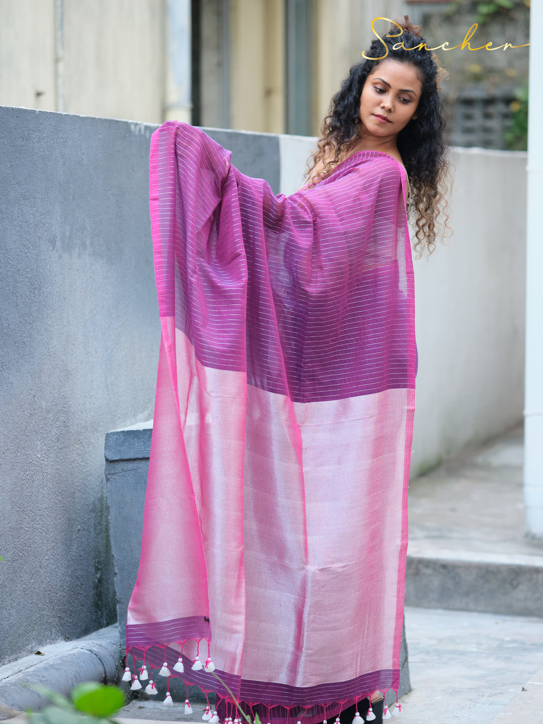 Woman displaying purple and pink striped mul cotton saree with tassels from Sancher, showcasing elegant workwear sarees available at saree boutiques in Anna Nagar.